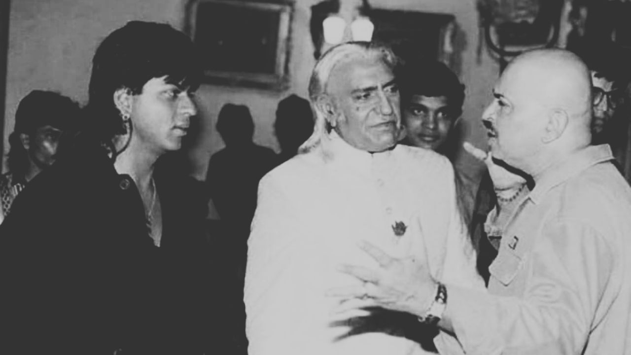 Shah Rukh Khan and Rakesh Roshan having a serious discussion on the set of the 1997 Bollywood film Koyla. Shah Rukh is in his character costume, while Rakesh Roshan looks focused and serious, as if debating a scene idea. The film set is filled with cameras, lighting, and props, creating a dramatic atmosphere